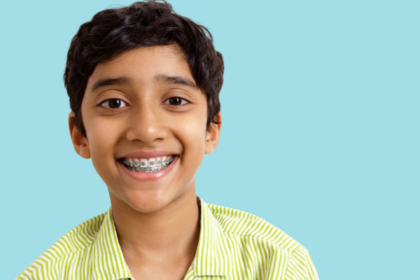 Child smiling with braces after an orthodontic evaluation, highlighting signs your child needs braces and the benefits of early orthodontic treatment.