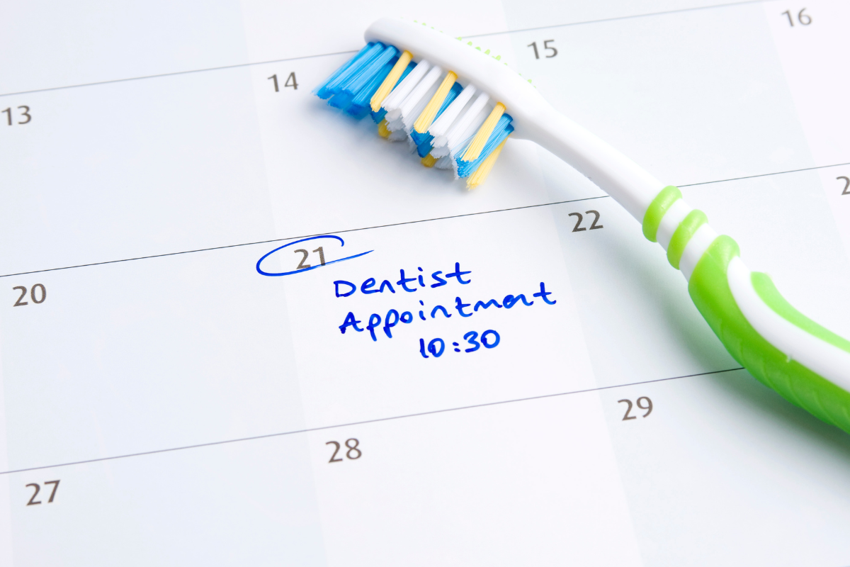Toothbrush resting on a calendar with a circled dentist appointment date and time, reminding patients to schedule their dental visit.
